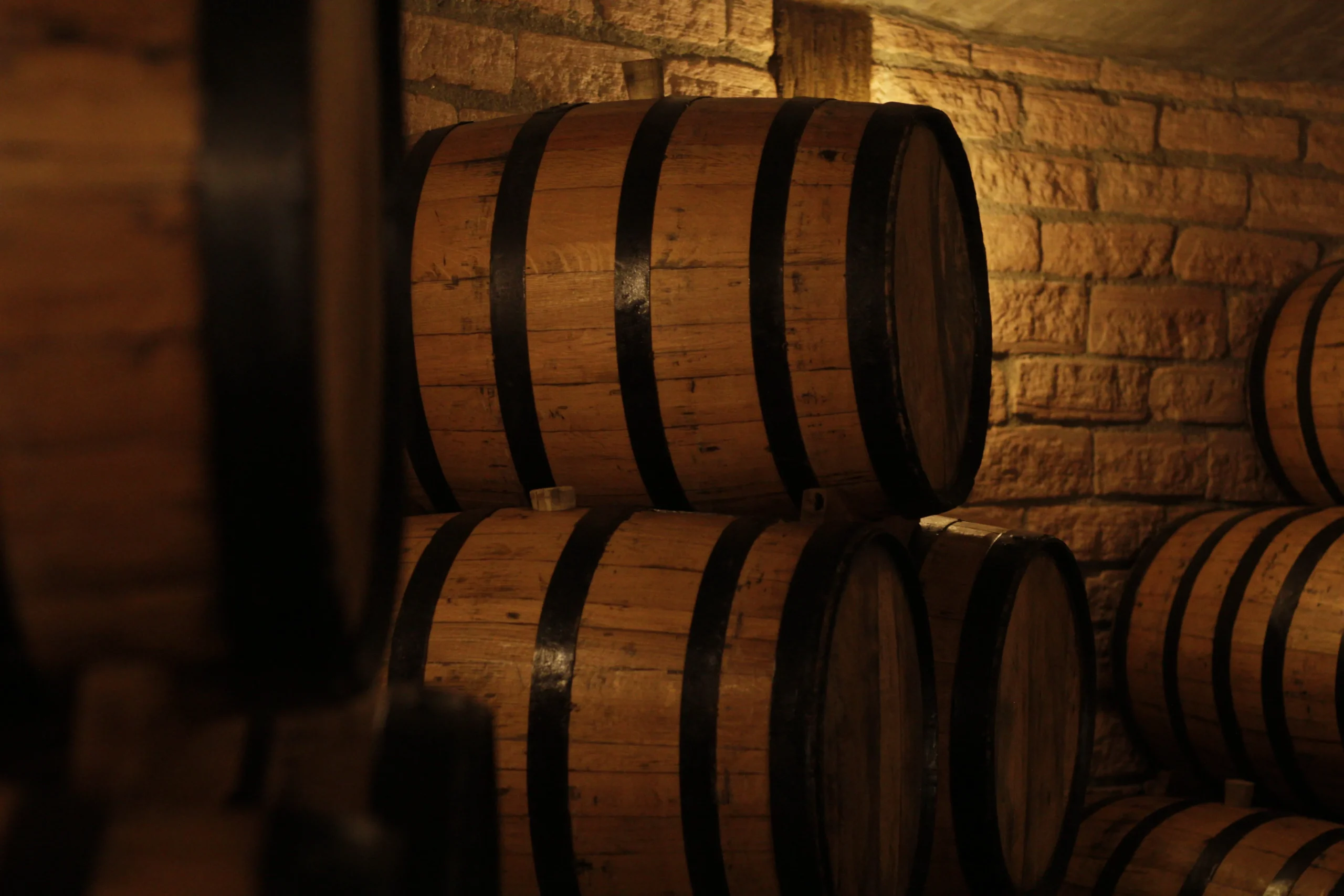 Rows of wooden whiskey barrels aging spirits in a distillery warehouse