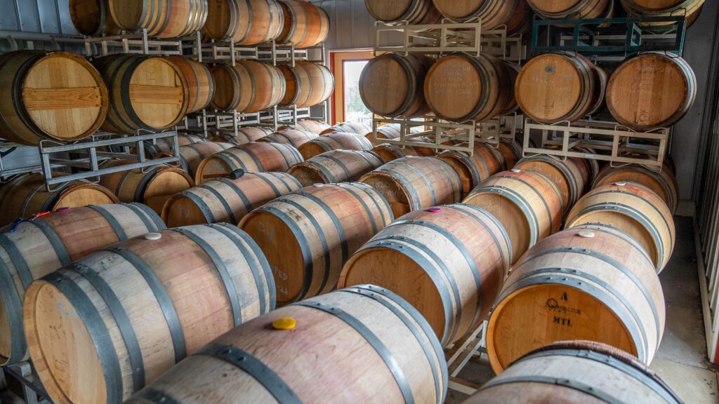 Used oak barrels stacked on racks in a barrel room